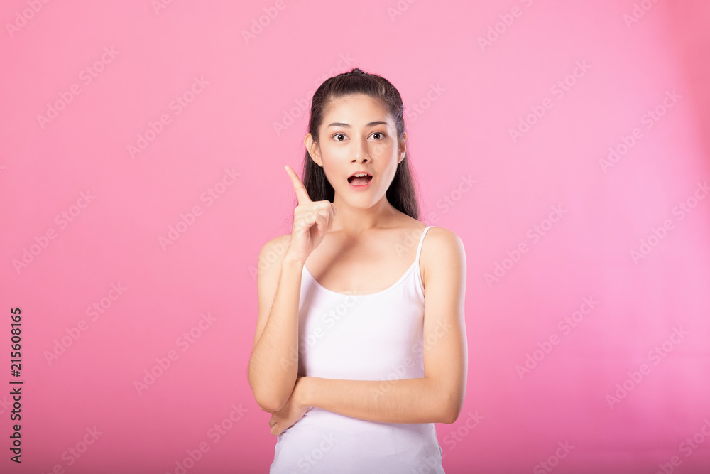 Portrait of a smiling attractive woman in white tanktop outfit with thinking pose while standing and smiling at camera isolated over pink background. Portrait of a smiling attractive woman in white tanktop outfit with thinking pose while standing and smiling at camera isolated over pink background.
