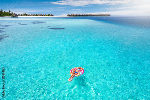 Attraktive Frau treibt auf aufblasbaren Lolli über das türkise Wasser der Malediven und genießt ihren Urlaub