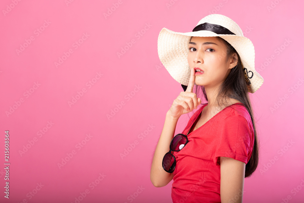 Portrait of attractive woman in summer outfit and hat posing secret hush while standing and looking at camera isolated over pink background. Portrait of attractive woman in summer outfit and hat posing secret hush while standing and looking at camera isolated over pink background.