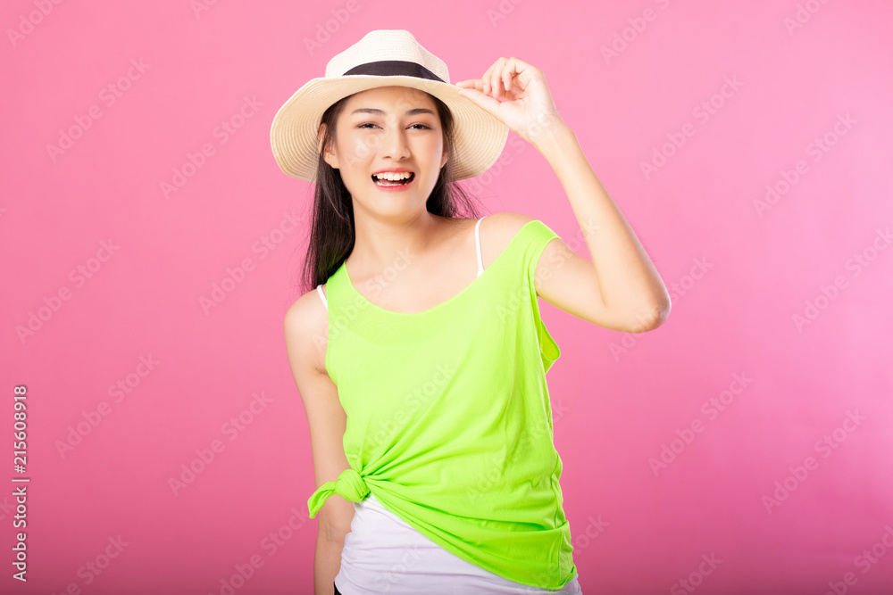 Portrait of a smiling attractive woman in green summer outfit and hat posing while standing and looking at camera isolated over pink background. Portrait of a smiling attractive woman in green summer outfit and hat posing while standing and looking at camera isolated over pink background.