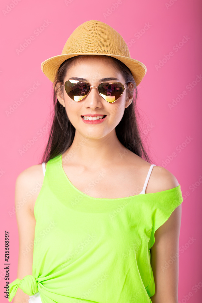 Portrait of a smiling attractive woman in green summer outfit and hat posing while standing and looking at camera isolated over pink background. Portrait of a smiling attractive woman in green summer outfit and hat posing while standing and looking at camera isolated over pink background.