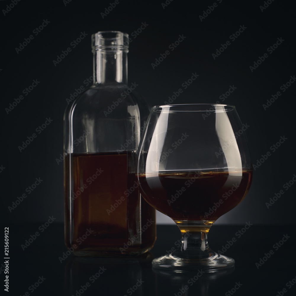 cognac glass and bottle on dark bg studio shot photo cognac glass and bottle on dark bg studio shot photo