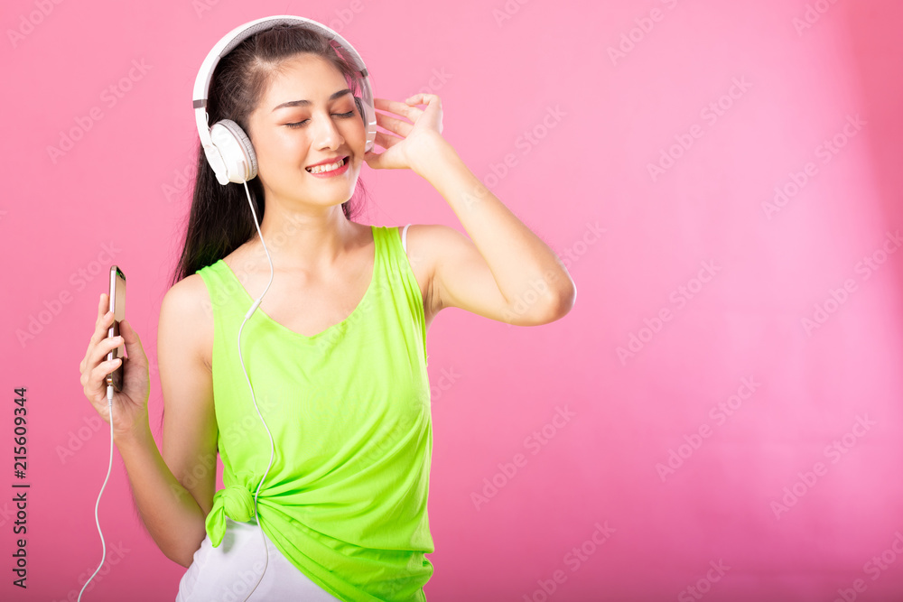 Portrait of a happy attractive woman in summer outfit listening and dancing to music with her headphones isolated over pink background. Portrait of a happy attractive woman in summer outfit listening and dancing to music with her headphones isolated over pink background.