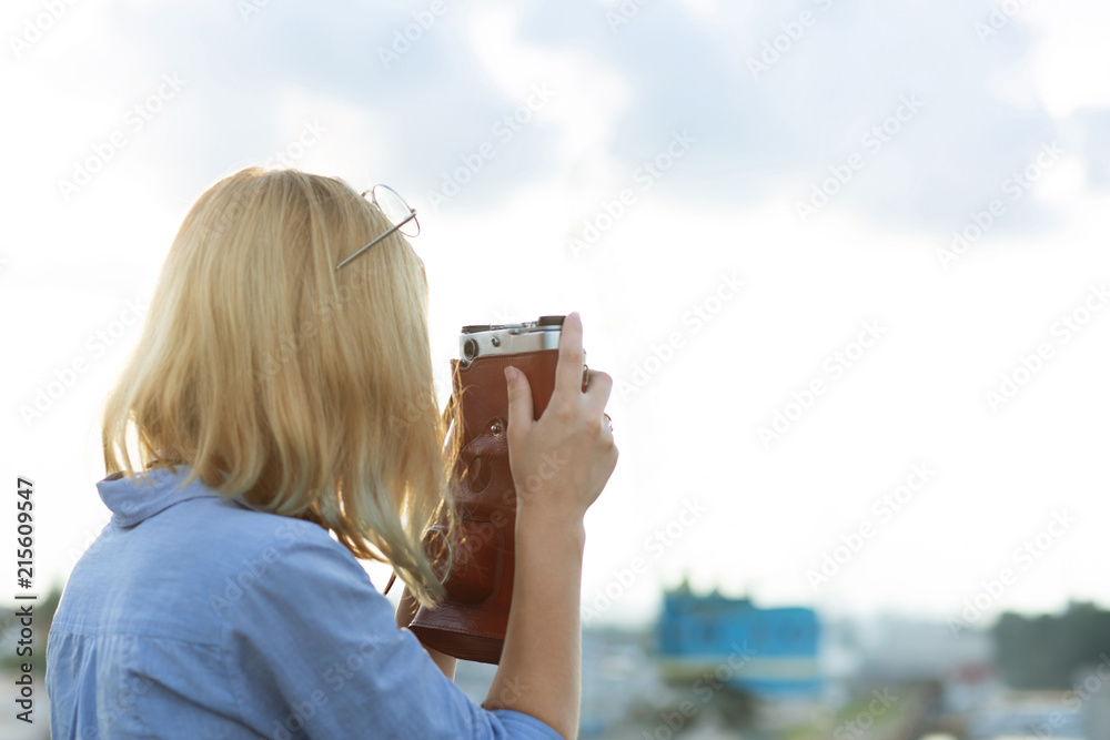 Young hipster girl photographer in blue shirt taking pictures on a vintage film camera. Space for text