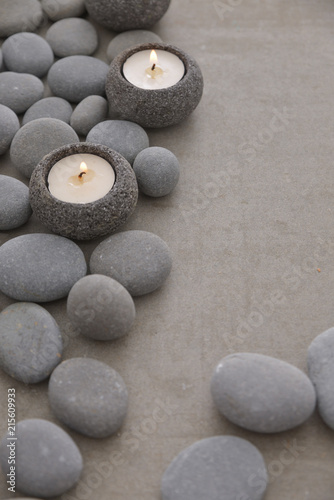 Pile of gray stones with candle and grey background