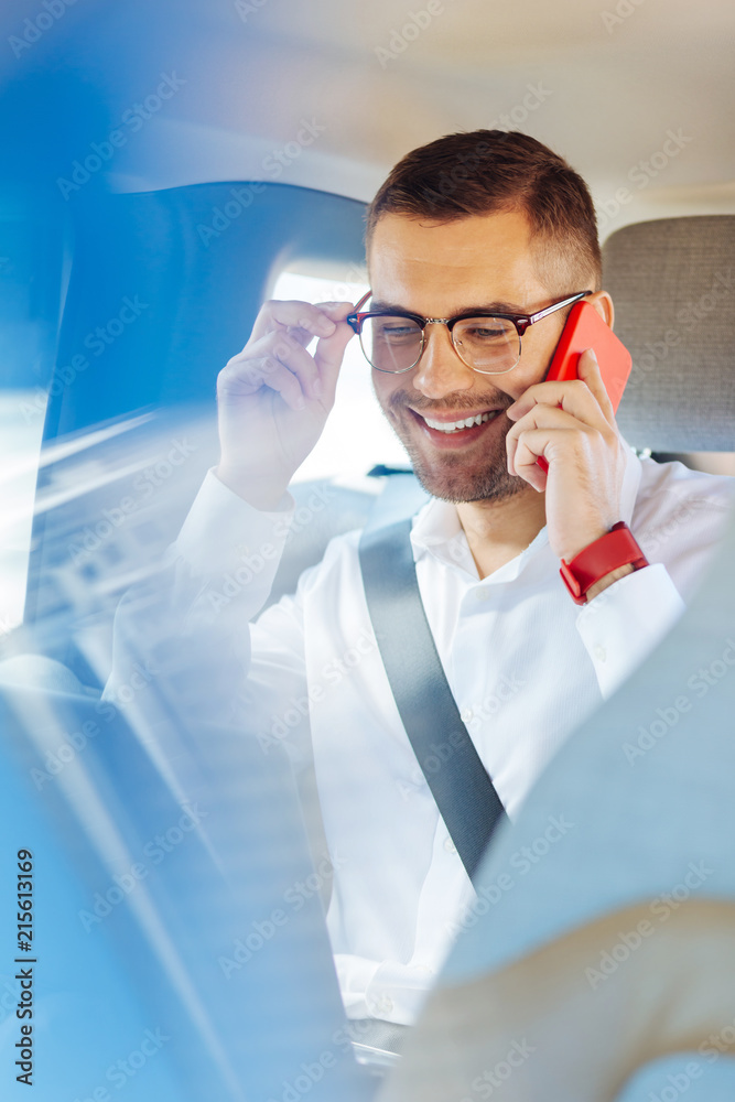 In touch. Positive cheerful businessman smiling while having a phone conversation with his colleague In touch. Positive cheerful businessman smiling while having a phone conversation with his colleague