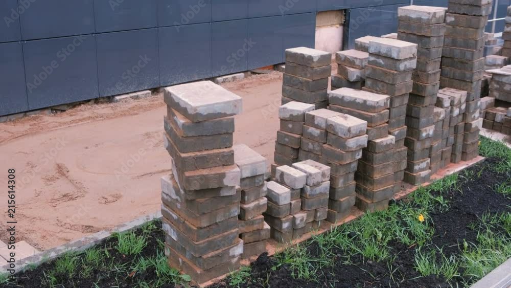 Laying paving slabs in front of the building. Sand and paving slabs in rows. Close-up view. Laying paving slabs in front of the building. Sand and paving slabs in rows. Close-up view.