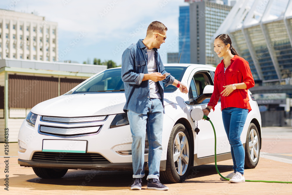 Pleasant interaction. Happy nice woman talking to her male friend while fuelling the car Pleasant interaction. Happy nice woman talking to her male friend while fuelling the car