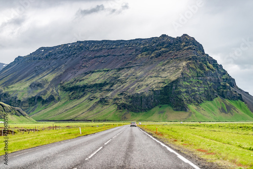 Iceland mountains landscape view of road trip, car, mountain cliff on cloudy day, south southern ring road or golden circle