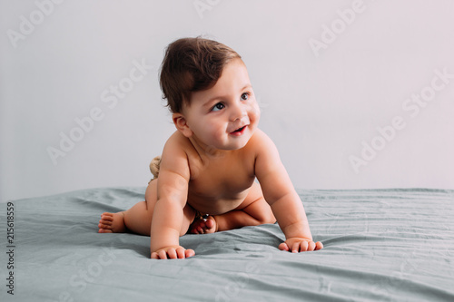 Beautiful baby crawling on the bed in the room, family lifestyle