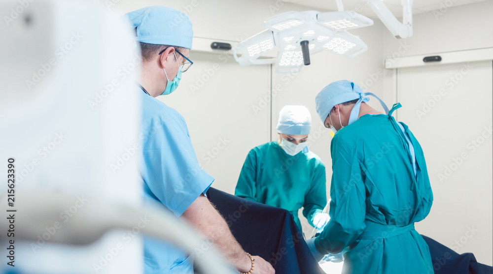View on team of surgeons operating over monitor and equipment in hospital View on team of surgeons operating over monitor and equipment in hospital