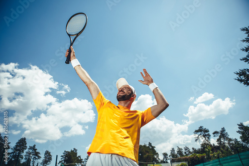 Low angle portrait beaming bearded male athlete holding sport equipment in hand while locating under blue sky during sunny day © Yakobchuk Olena