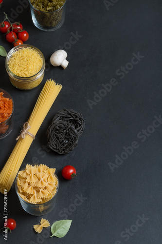 Different types of Italian pasta with vegetables on the dark chalkboard