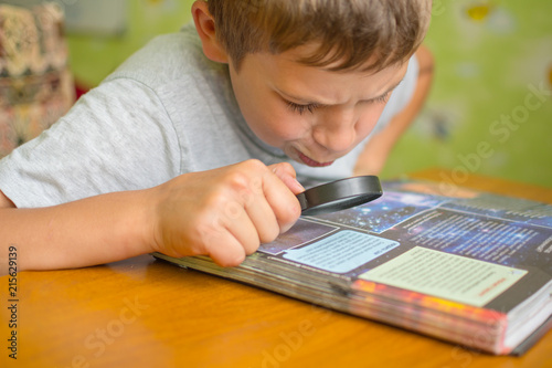 boy reading a book with a magnifying glass