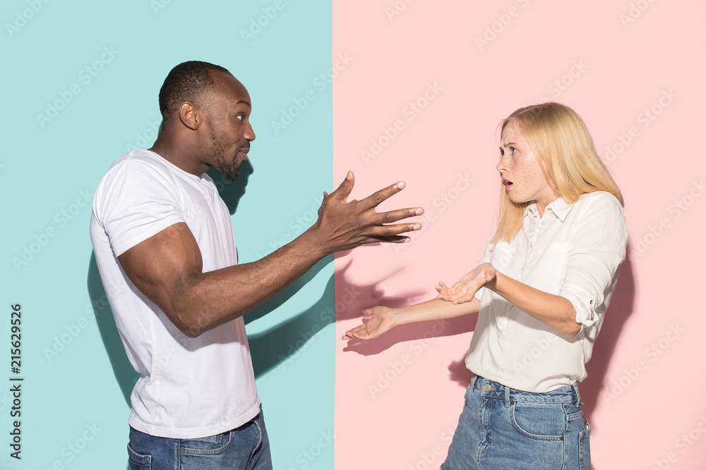 Beautiful female and male portrait on pink and blue studio backgroud. The young emotional couple Beautiful female and male portrait on pink and blue studio backgroud. The young emotional couple