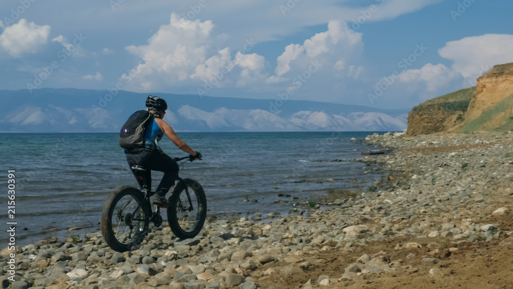 Fototapeta premium Fat bike also called fatbike or fat-tire bike in summer driving on the beach. The guy is going straight on the beach. On the sand on such a bike ride is not difficult.