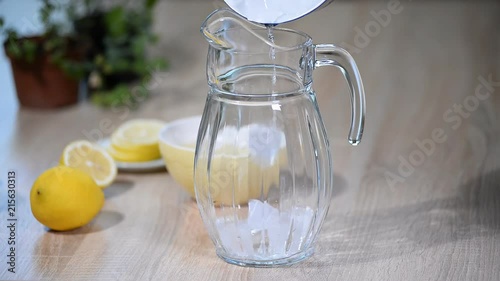 Preparation of the lemonade drink. Lemonade in the jug and lemons with mint on the table photo
