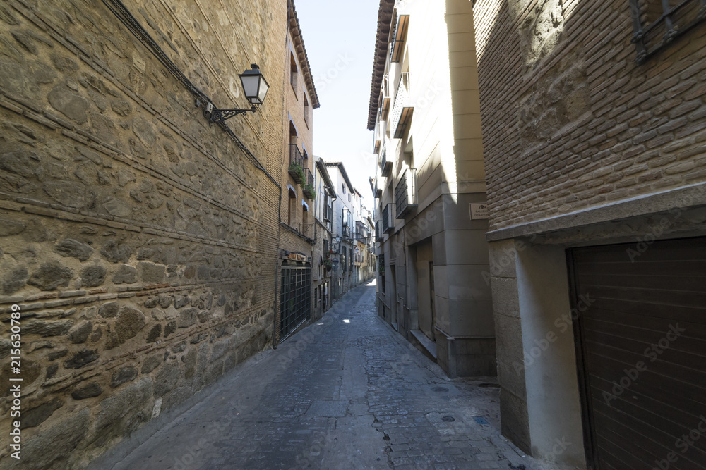 Medieval cobbled and stepped street with flowery balconies and public lighting lamps in the city of Toledo. Spain
