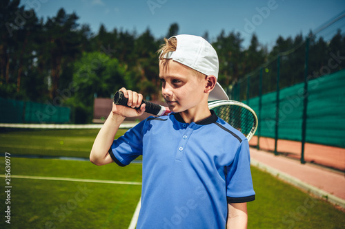 Pensive child holding sport tool in hand during game on contemporary court photo