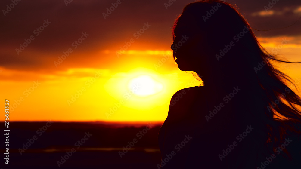 silhouette of a beautiful girl at sunset in a field, face profile of young woman silhouette of a beautiful girl at sunset in a field, face profile of young woman