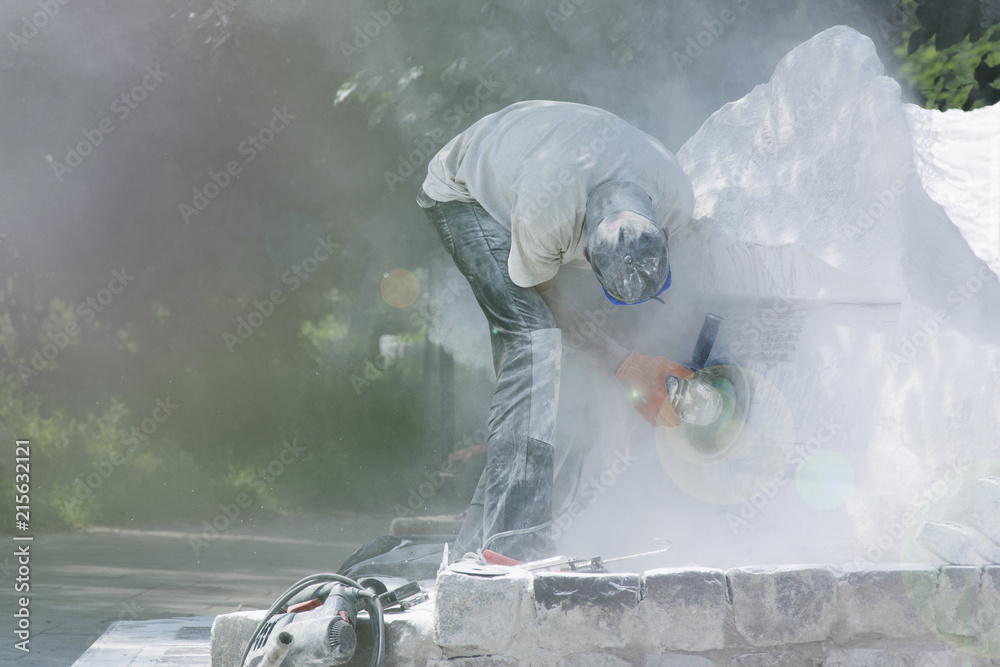 The worker performs grinding work on the monument in the park. The worker performs grinding work on the monument in the park.