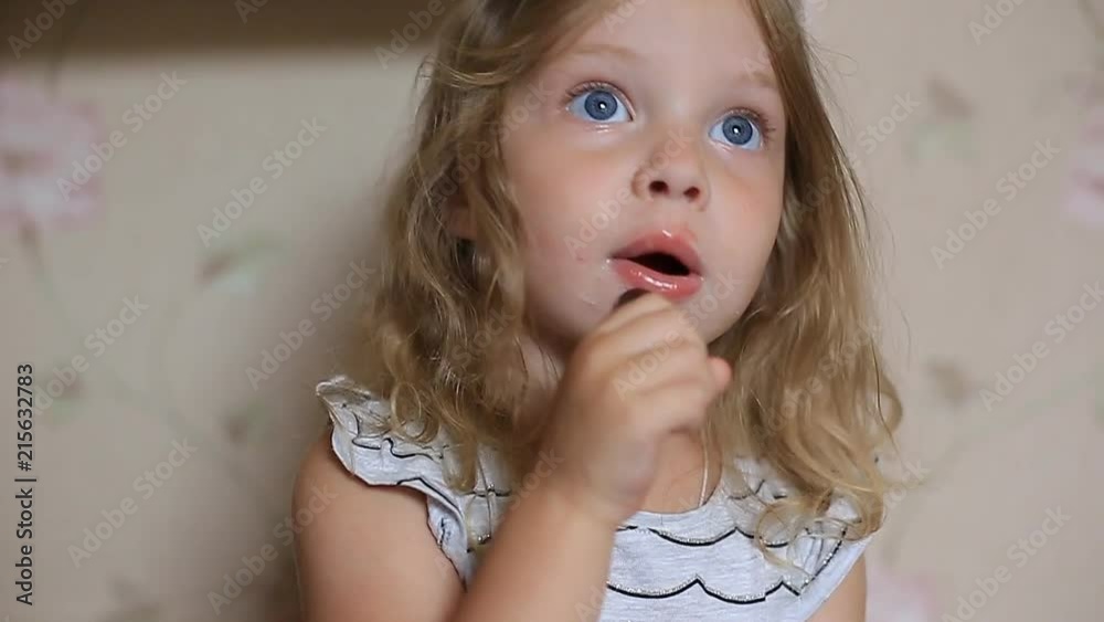 a little two-year-old girl paints her lips with her mother's lipstick. a little two-year-old girl paints her lips with her mother's lipstick.