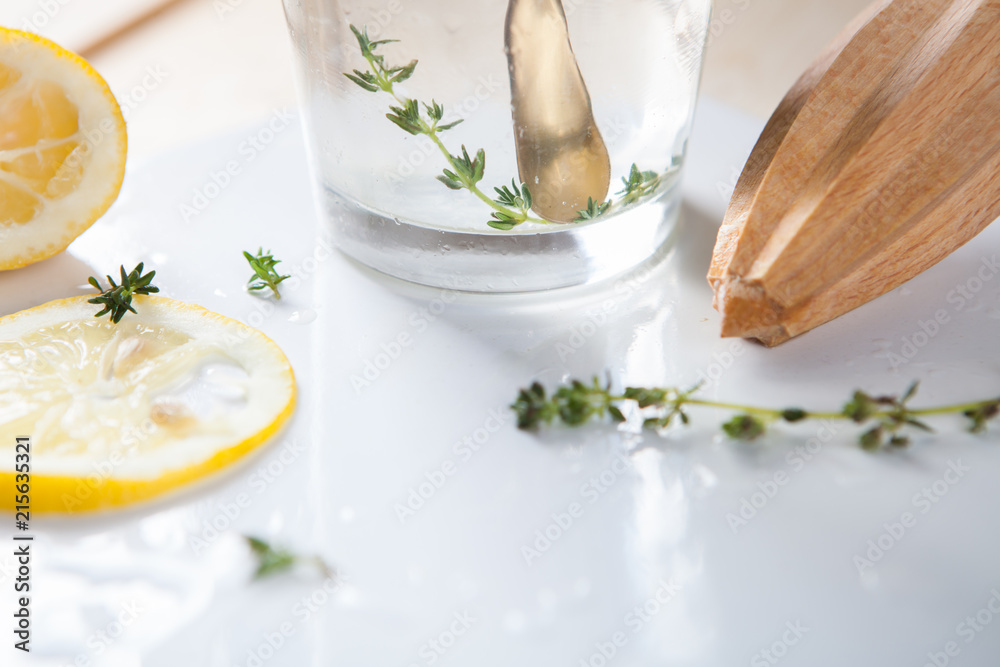 Bleak passing through a glass with lemonade, a juicer and a twig of thyme on a white tray Bleak passing through a glass with lemonade, a juicer and a twig of thyme on a white tray
