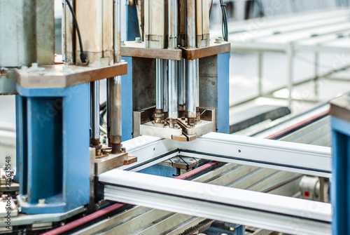 Manual worker assembling glass panels for PVC windows. Factory for aluminum and PVC windows and doors production. Automatic line machine for sticking together PVC sections of window for the final step