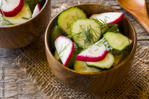 Healthy salad with radishes and cucumbers in a wooden bowl. photo