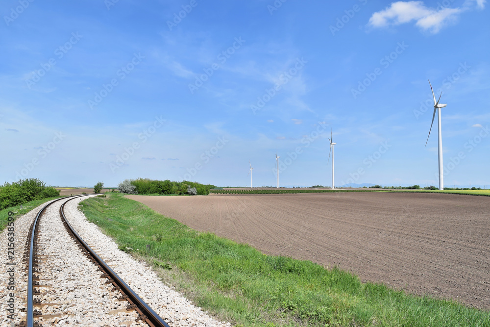 Railroad track perspective and wind farm Alibunar (Serbia) in background   