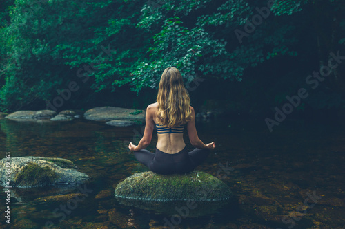 Fototapeta Naklejka Na Ścianę i Meble -  Woman meditating on rock in river