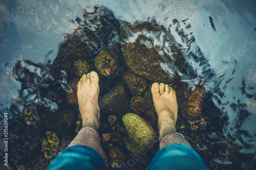 Vászonkép Feet of young man standing in river