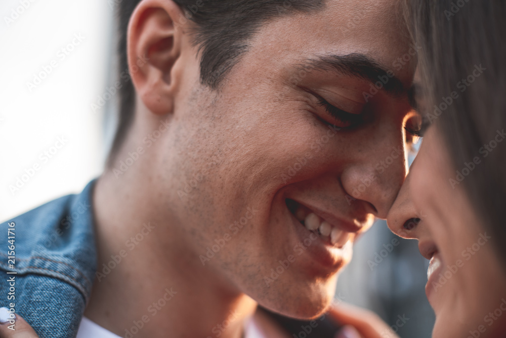 Close up focus on male face showing sincere joy to girlfriend. They are standing in front of each other and laughing with content Close up focus on male face showing sincere joy to girlfriend. They are standing in front of each other and laughing with content