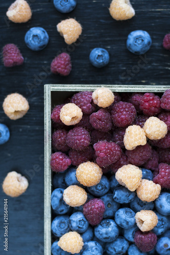 Fresh flavored blueberries and raspberries like a background in dark colors