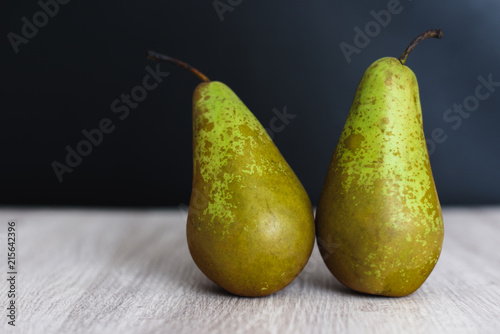 A couple of fresh ripe organic green pears on dark and wooned background.