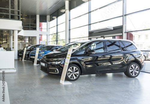 Shiny cars standing in a row in bright elegant car rental interior with windows on wall