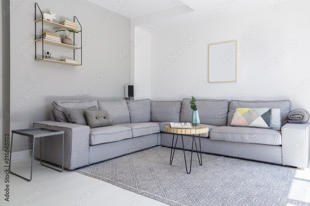 Grey corner sofa and wooden table in spacious living room interior with ...