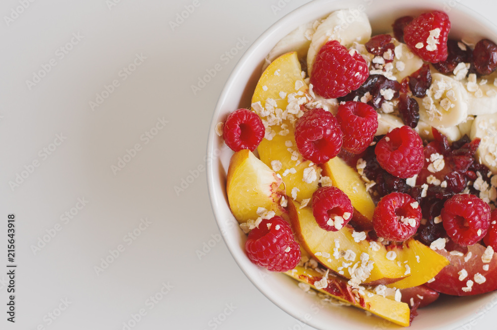 Salad with nectarine, banana, raspberry, dried cranberry, plum and quick cook oats in a bowl. Breakfast meal. Fruit dessert Salad with nectarine, banana, raspberry, dried cranberry, plum and quick cook oats in a bowl. Breakfast meal. Fruit dessert