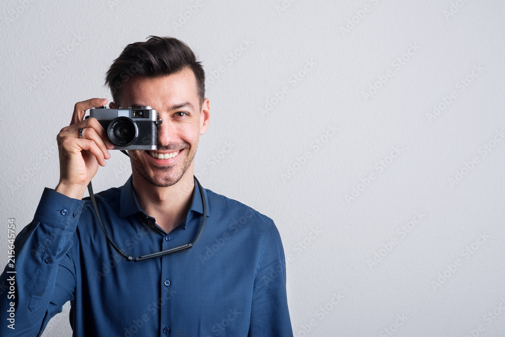 Portrait of a young man in a studio with a camera on front of his eye. Copy space. Portrait of a young man in a studio with a camera on front of his eye. Copy space.