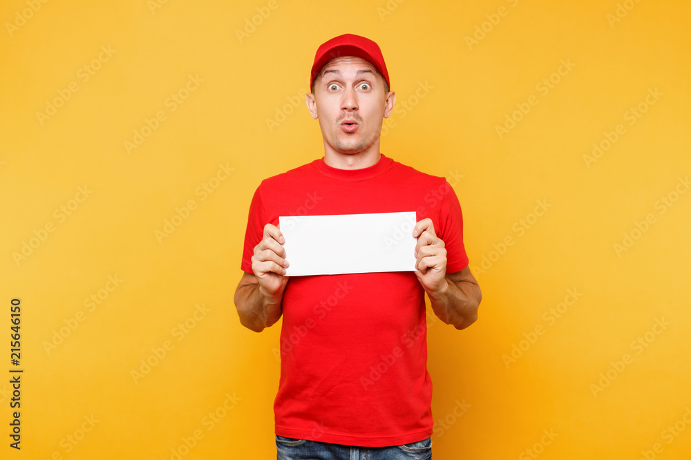 Delivery man in red uniform isolated on yellow orange background. Professional male employee courier in cap, t-shirt hold white empty blank paper. Service concept. Copy space place for text or image.