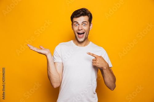 Portrait of a cheerful young man pointing fingers away