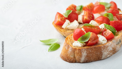 Bruschetta with tomatoes, mozzarella cheese and basil on a light background. Traditional italian appetizer or snack, antipasto. Top view with copy space. Flat lay