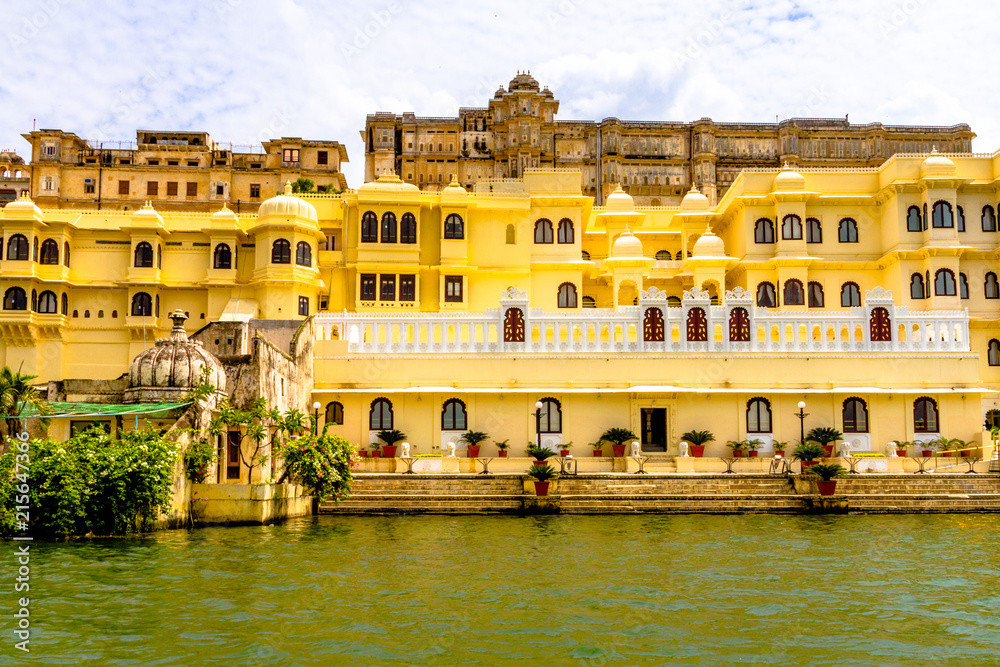 View from Lake Pichola onto yellow platial buildings in Udaipur, India