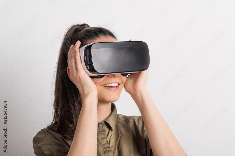 Portrait of a young beautiful woman with VR goggles in studio.
