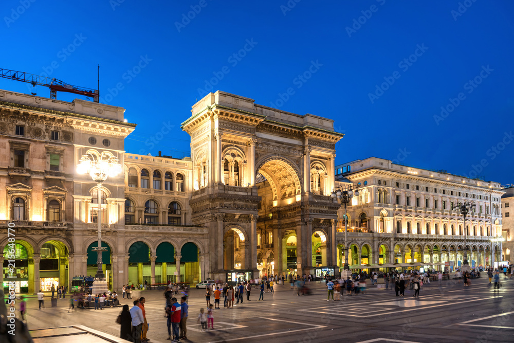Obraz premium Ludzie idący w pobliżu galerii Vittorio Emanuele II na placu Duomo, Mediolan, Włochy. Nocny widok ulicy i budynków