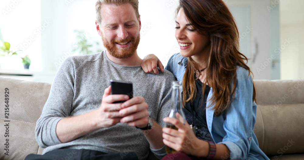 Relaxed couple or friends using mobile phone together to shop online Relaxed couple or friends using mobile phone together to shop online