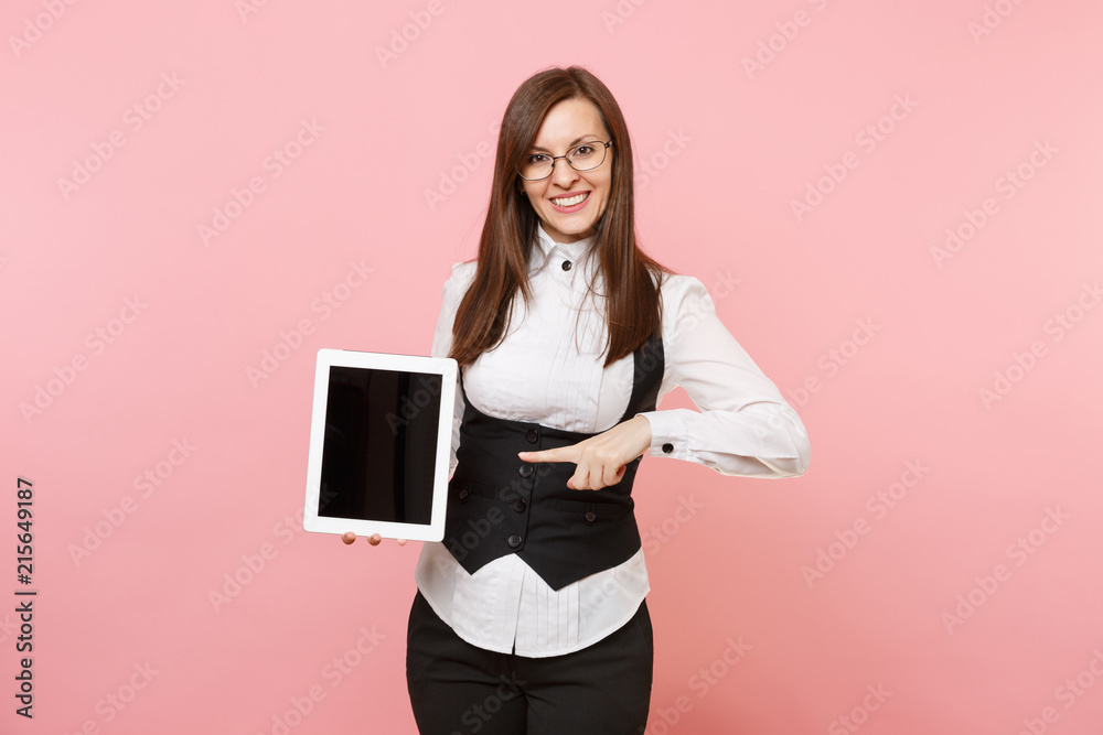Young smiling business woman in glasses pointing finger on tablet pc computer with blank empty screen isolated on pink background. Lady boss. Achievement career wealth. Copy space for advertisement. Young smiling business woman in glasses pointing finger on tablet pc computer with blank empty screen isolated on pink background. Lady boss. Achievement career wealth. Copy space for advertisement.