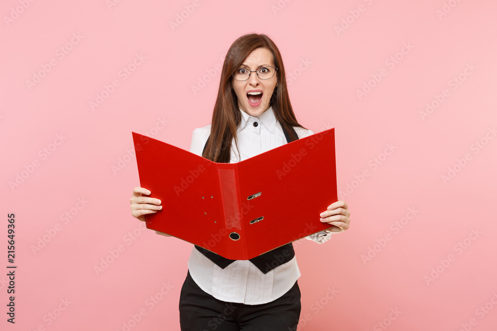 Young irritated business woman in glasses scream holding red folder for papers document isolated on pastel pink background. Lady boss. Achievement career wealth concept. Copy space for advertisement. Young irritated business woman in glasses scream holding red folder for papers document isolated on pastel pink background. Lady boss. Achievement career wealth concept. Copy space for advertisement.