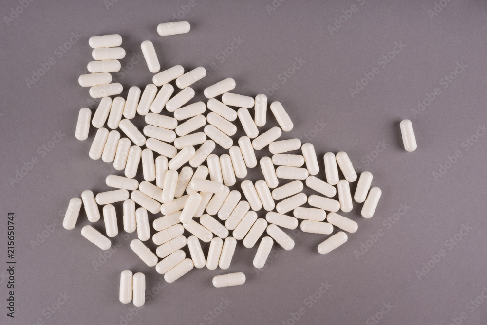 White pills isolated on pastel coloured background. Medication and prescription pills flat lay background.