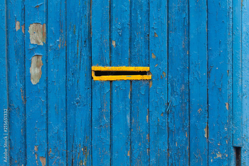 Old painted blue wooden fence with a yellow slit Old painted blue wooden fence with a yellow slit